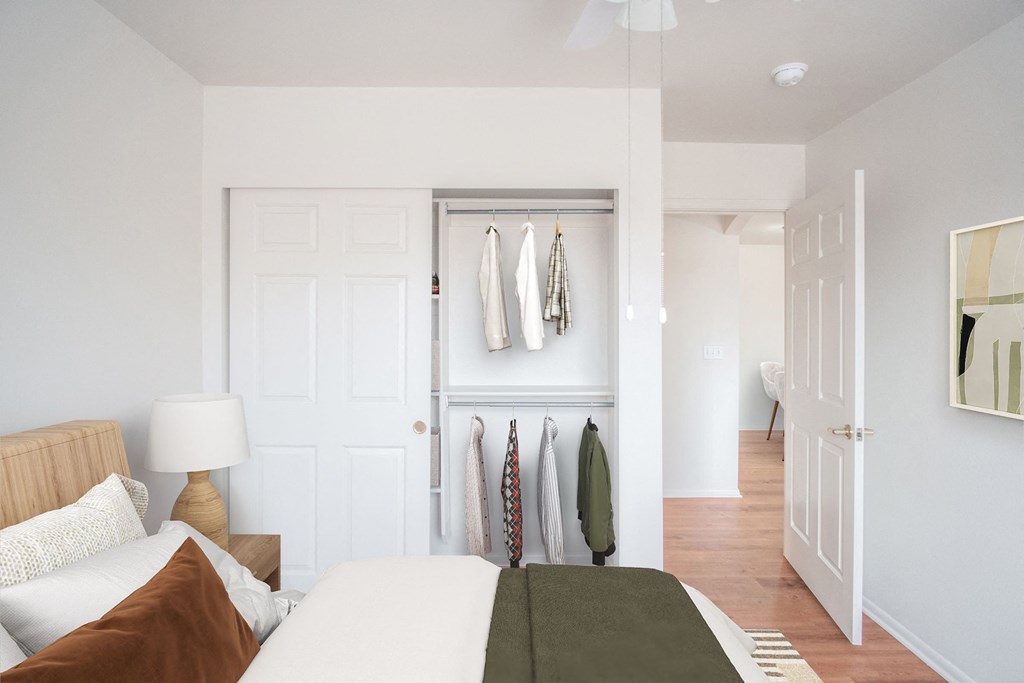 a bedroom with a bed and a closet with clothes