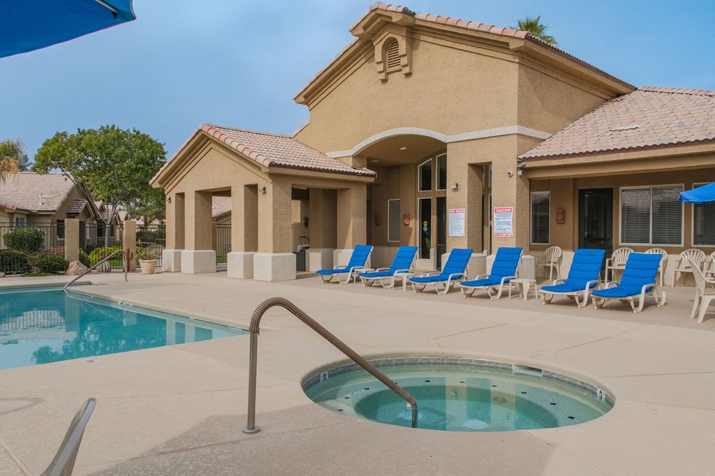 a swimming pool with blue chairs in front of a building