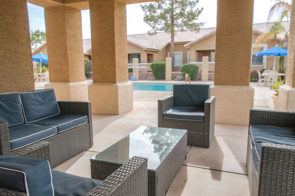 a patio with chairs and a table in front of a pool