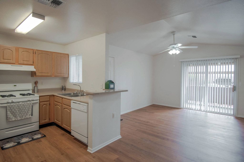 an empty kitchen and living room with wood flooring and a window