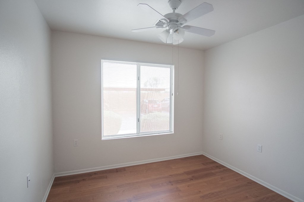 an empty room with a ceiling fan and a window
