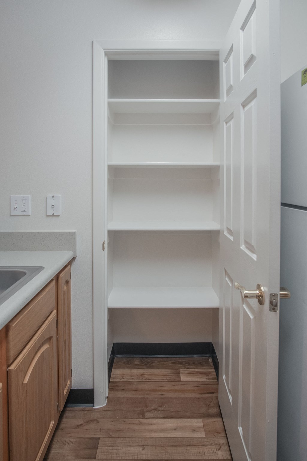 an empty kitchen with white shelves and a refrigerator