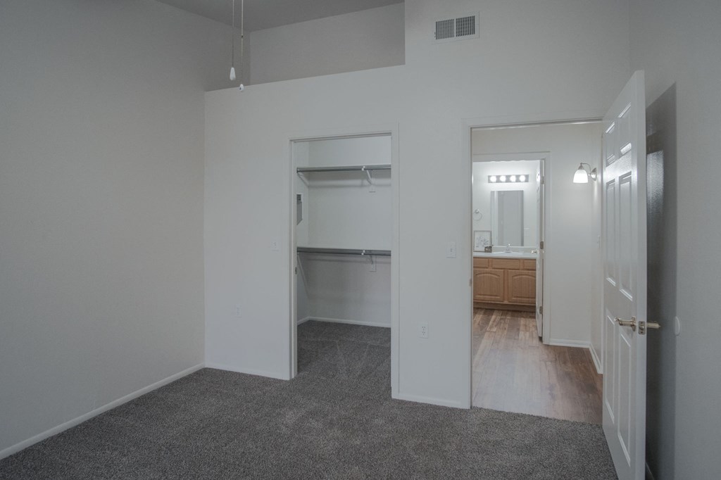 an empty living room with a hallway to a bathroom and a kitchen
