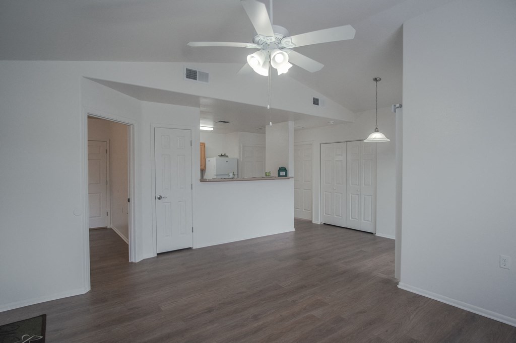 an empty living room with white walls and a ceiling fan