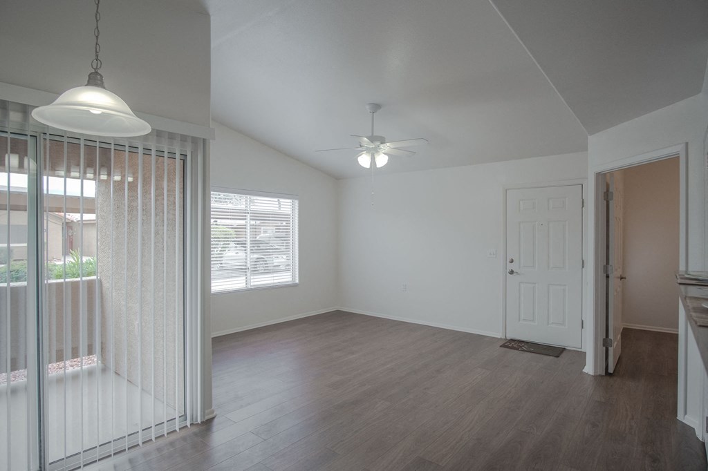 an empty living room with a white door and a ceiling fan