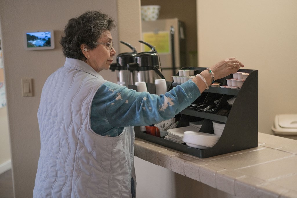 a woman prepares food in a kitchen on a laptop