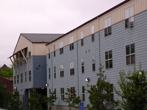 A large building with a blue and beige exterior and a carport.
