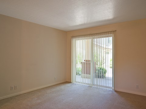 an empty living room with a sliding glass door to a patio