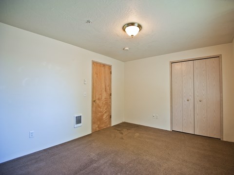 an empty living room with a door to a closet