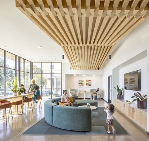 A woman and two children are sitting on a couch in a room with a wooden ceiling.