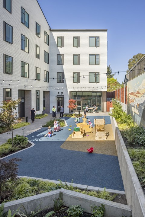 A playground area with children playing in the middle of a courtyard surrounded by buildings.