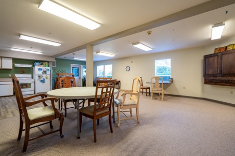 a community room with a round table and chairs and a kitchen