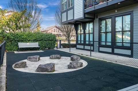 a park with a bench and rocks in front of a building