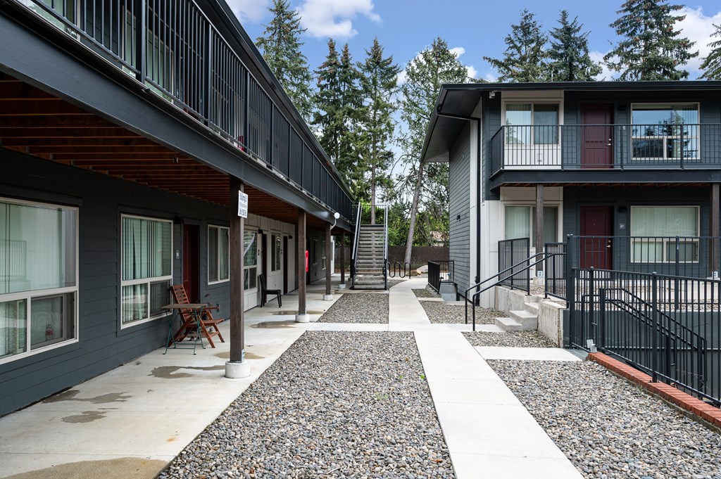 A long, narrow walkway with a black railing separates two buildings.