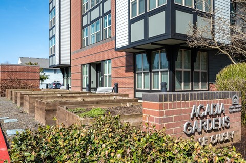 a picture of the front of a building with a sign that reads acadia gardens