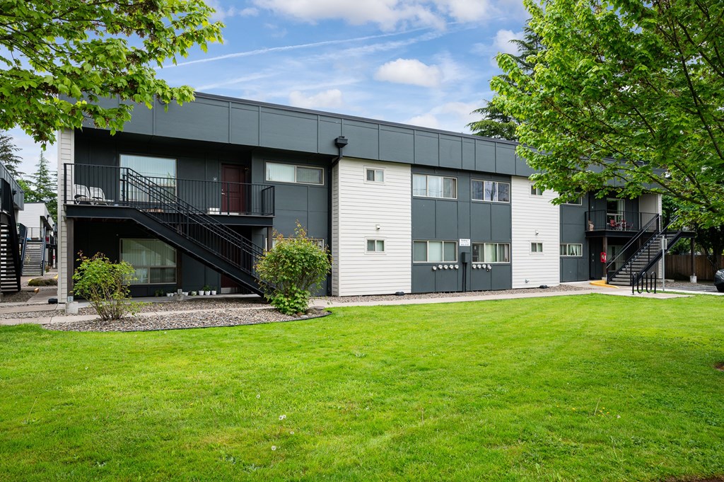 A modern apartment building with a green lawn in front.