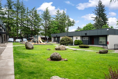 A playground with a slide and a green lawn.