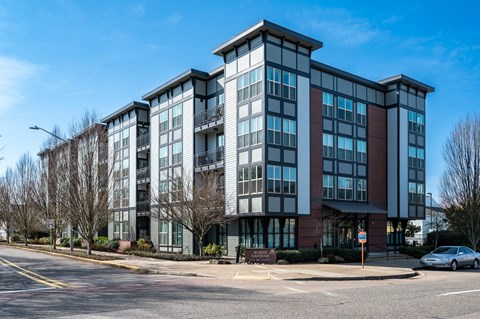 an apartment building on a street corner with a blue sky in the background