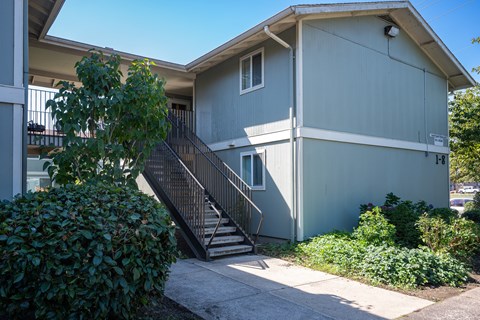 A grey house with a black metal staircase leading to the front door.