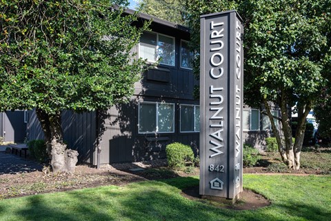 A sign for Walnut Court stands in front of a building.