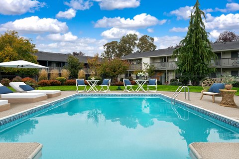 A swimming pool surrounded by lounge chairs and trees.