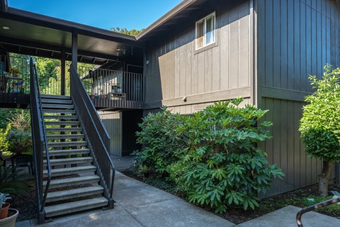 A house with a wooden exterior and a staircase leading to a balcony.