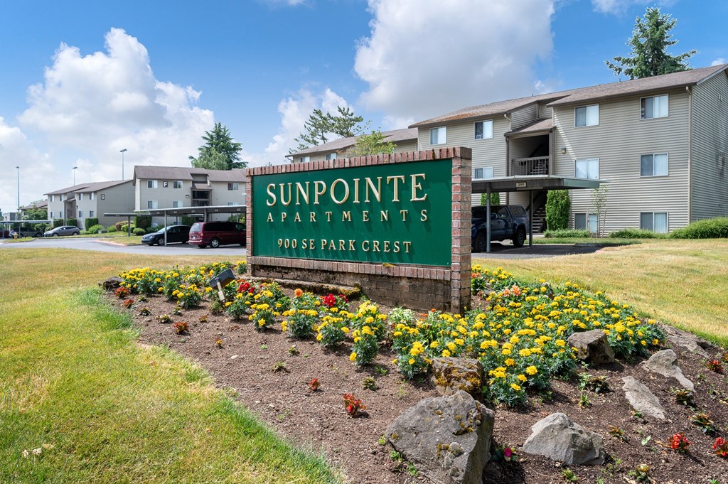 a sign for suffolk apartments sits in a flower bed in front of a building