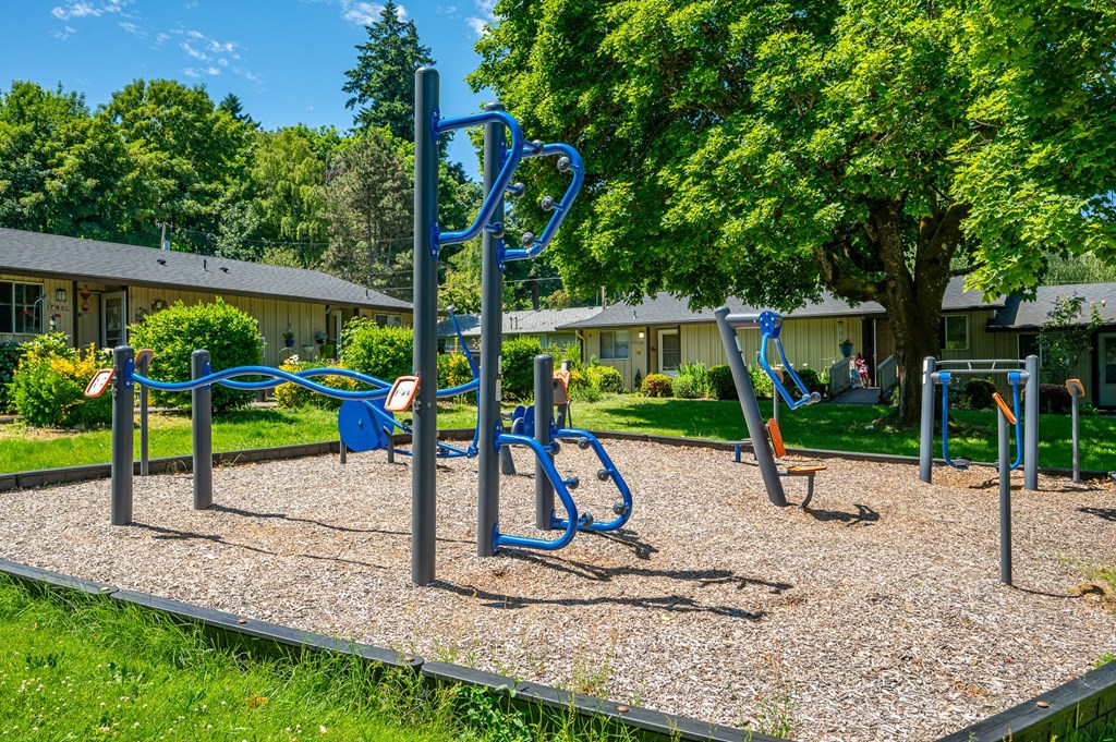 A playground with a blue swing set and a gravel ground.