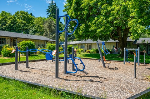 A playground with a blue swing set and a gravel ground.