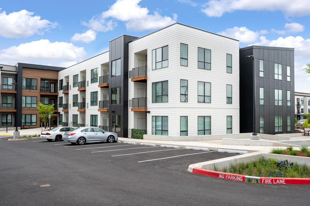 A modern apartment complex with a car parked in the lot.