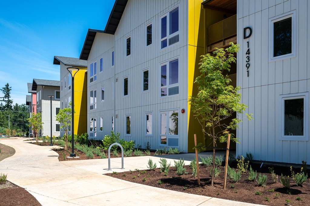 a building with a sidewalk and plants in front of it