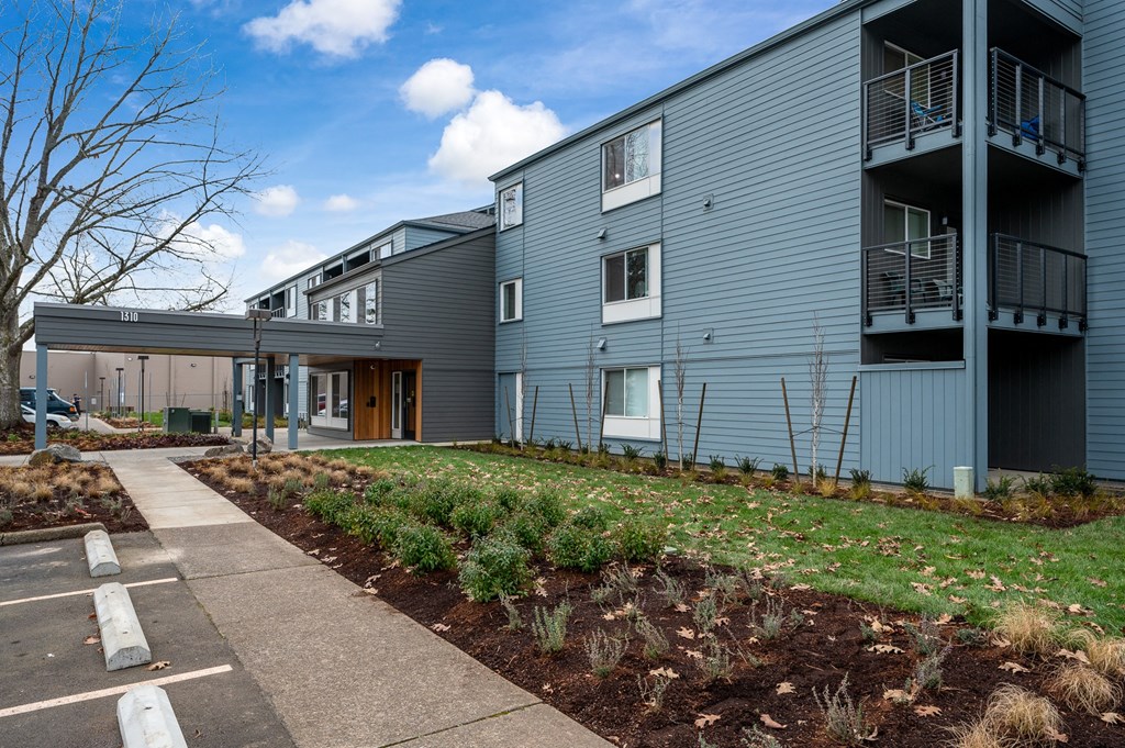 the exterior of a blue apartment building with a sidewalk