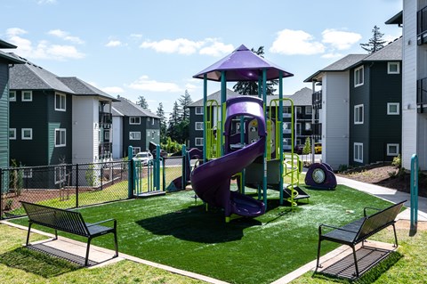 A playground with a purple slide and two benches.