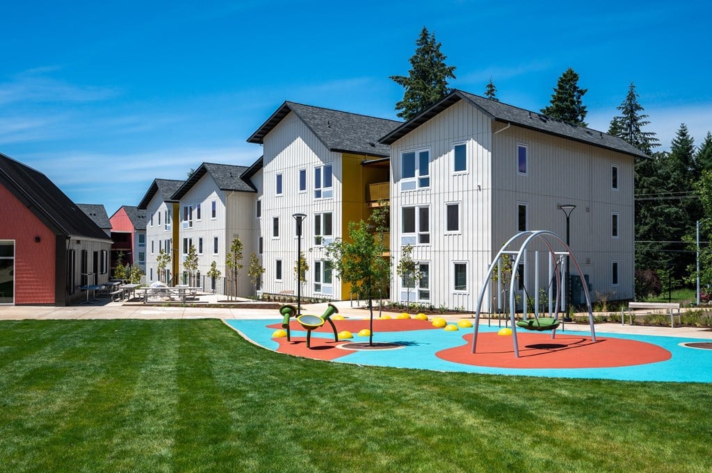 a playground in front of an apartment complex with children playing on it