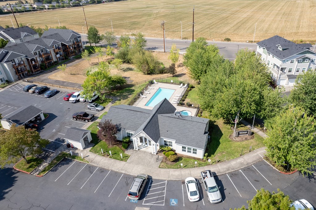 A parking lot with a few cars and a building with a pool in the background.