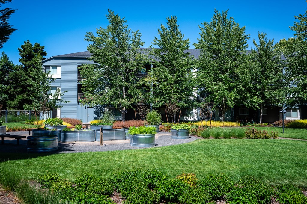 a garden with benches and trees in front of a building