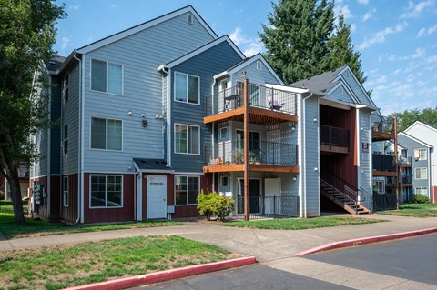 A two-story apartment building with a red door and a balcony.