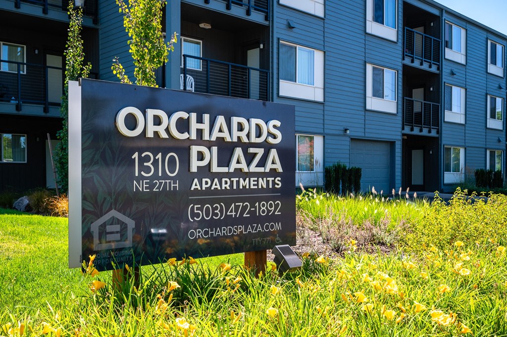 a sign sits in the grass in front of an apartment building