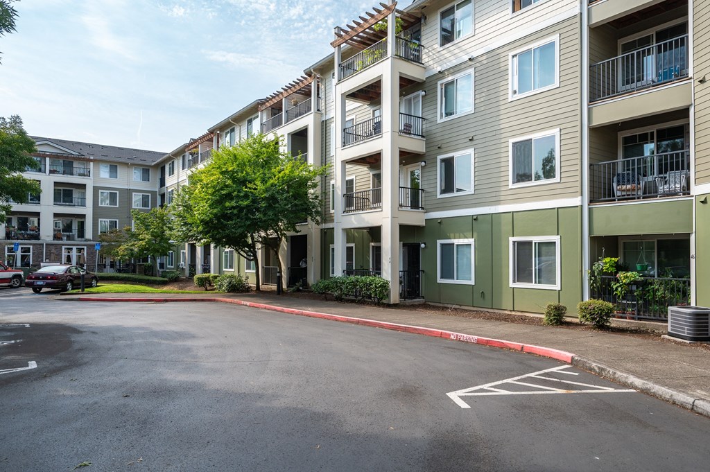 A parking lot in front of a multi-story apartment building.