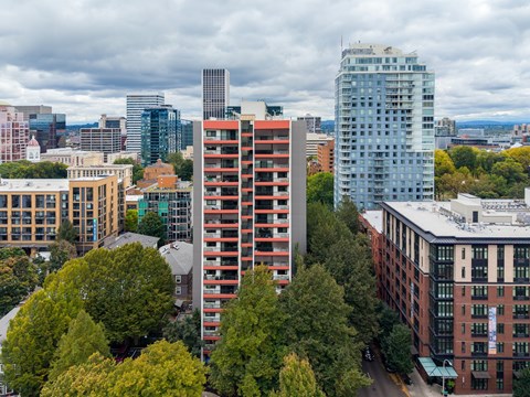 A cityscape with a mix of modern and older buildings, with trees in the foreground.