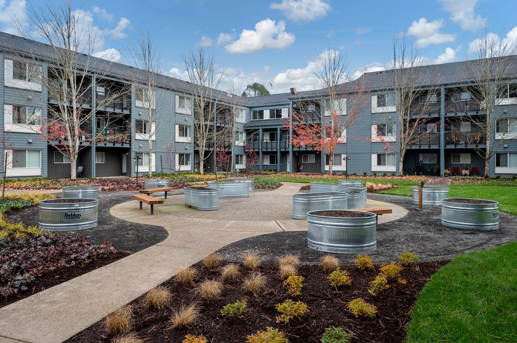 a courtyard with benches and trees in front of an apartment building