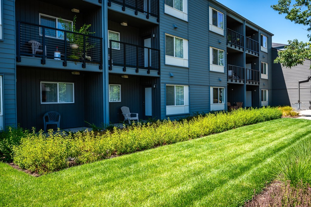 a row of apartment buildings with green grass and yellow flowers