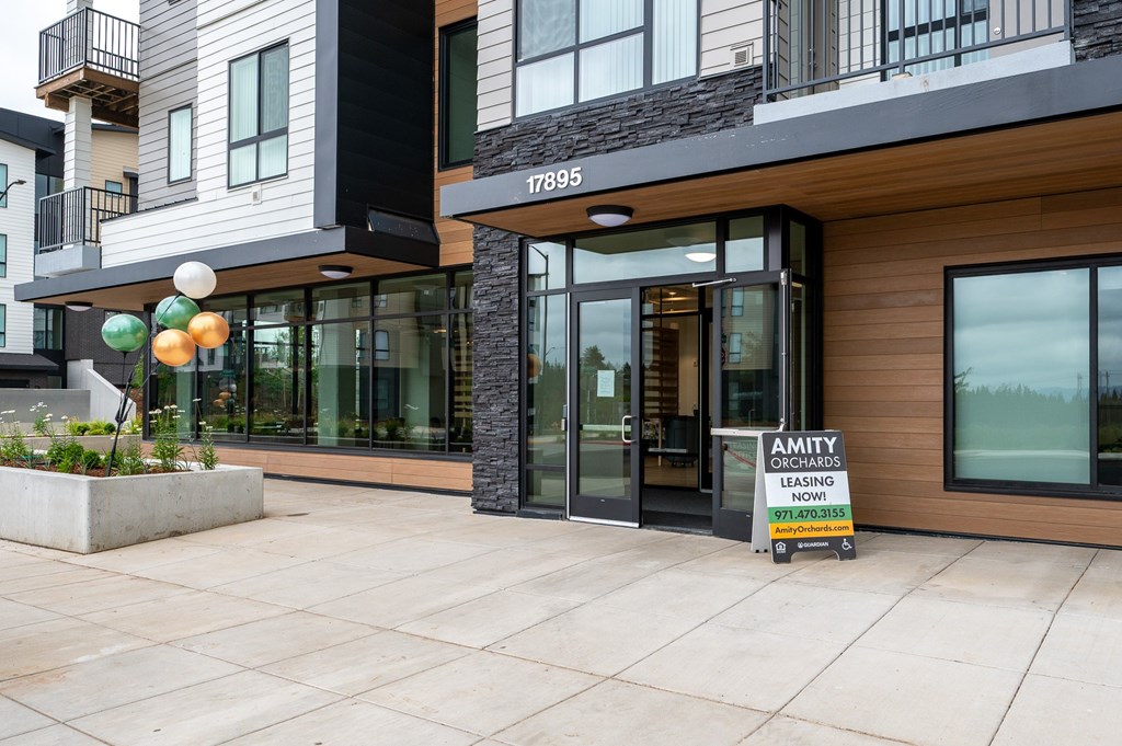 A modern building with a leasing sign in front.