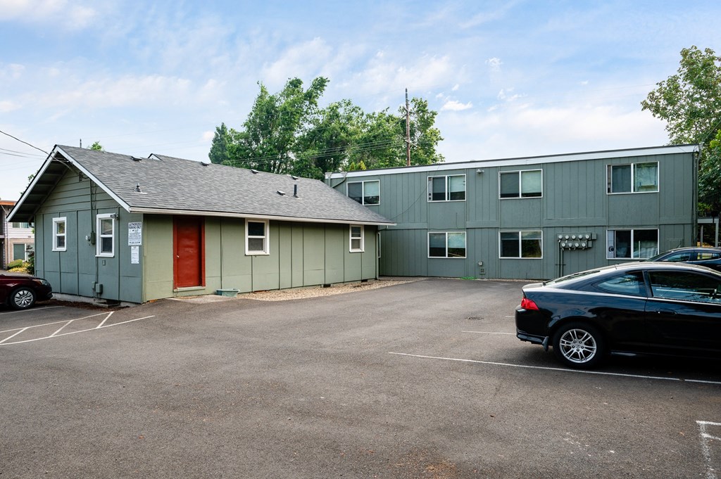 a large green building with a parking lot and cars