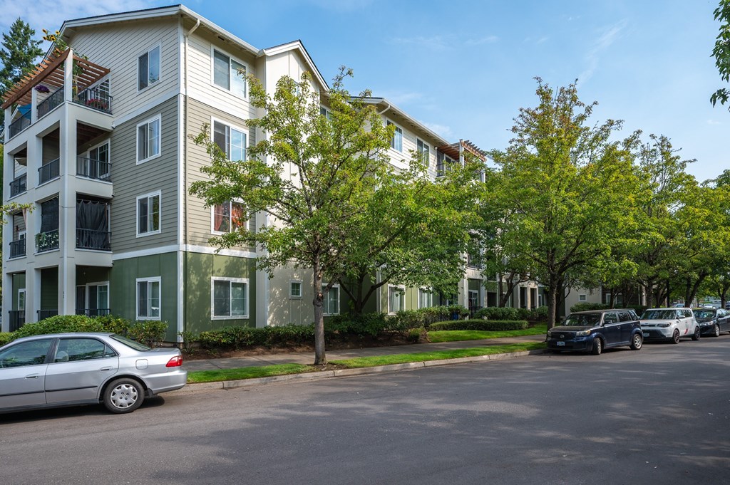 A silver car is parked in front of a two-story apartment building.