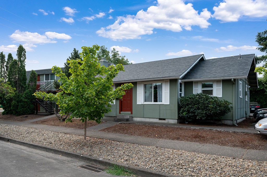 a green house with a red door and a tree in front of it