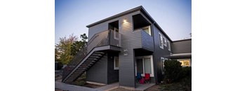 A grey two story house with a balcony on the upper floor.