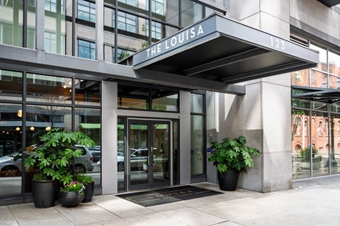 The Louisa building has a glass entrance with a black mat in front.