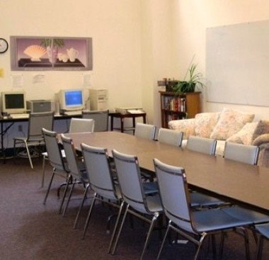 A conference room with a long table surrounded by chairs.