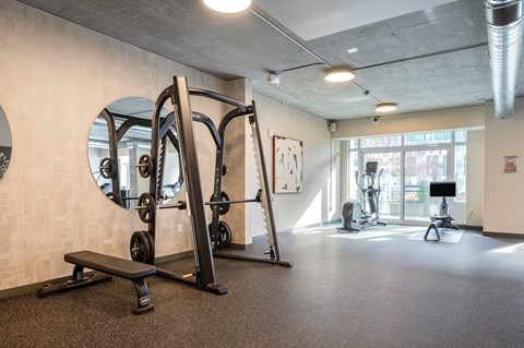 A gym with a mirror, weights, and exercise equipment.